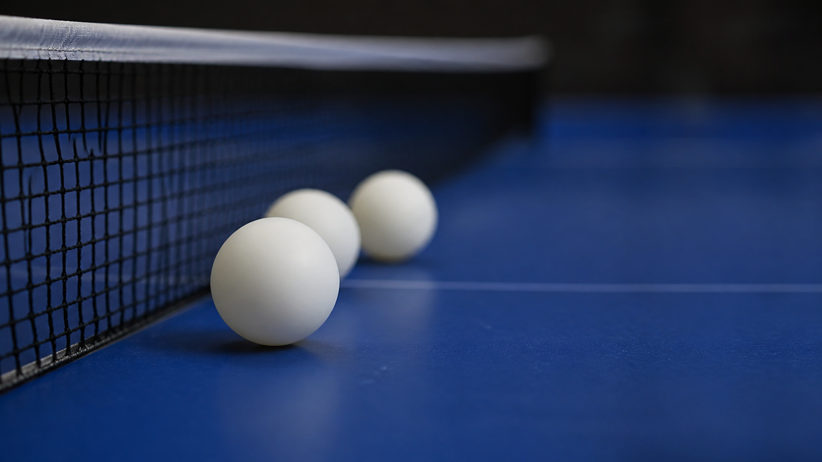Fehér asztalitenisz labdák kék pingpongasztalon, a háló mellett